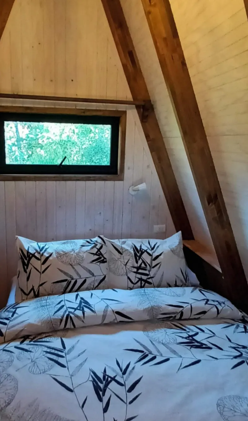 Double bed with a window onto the forest