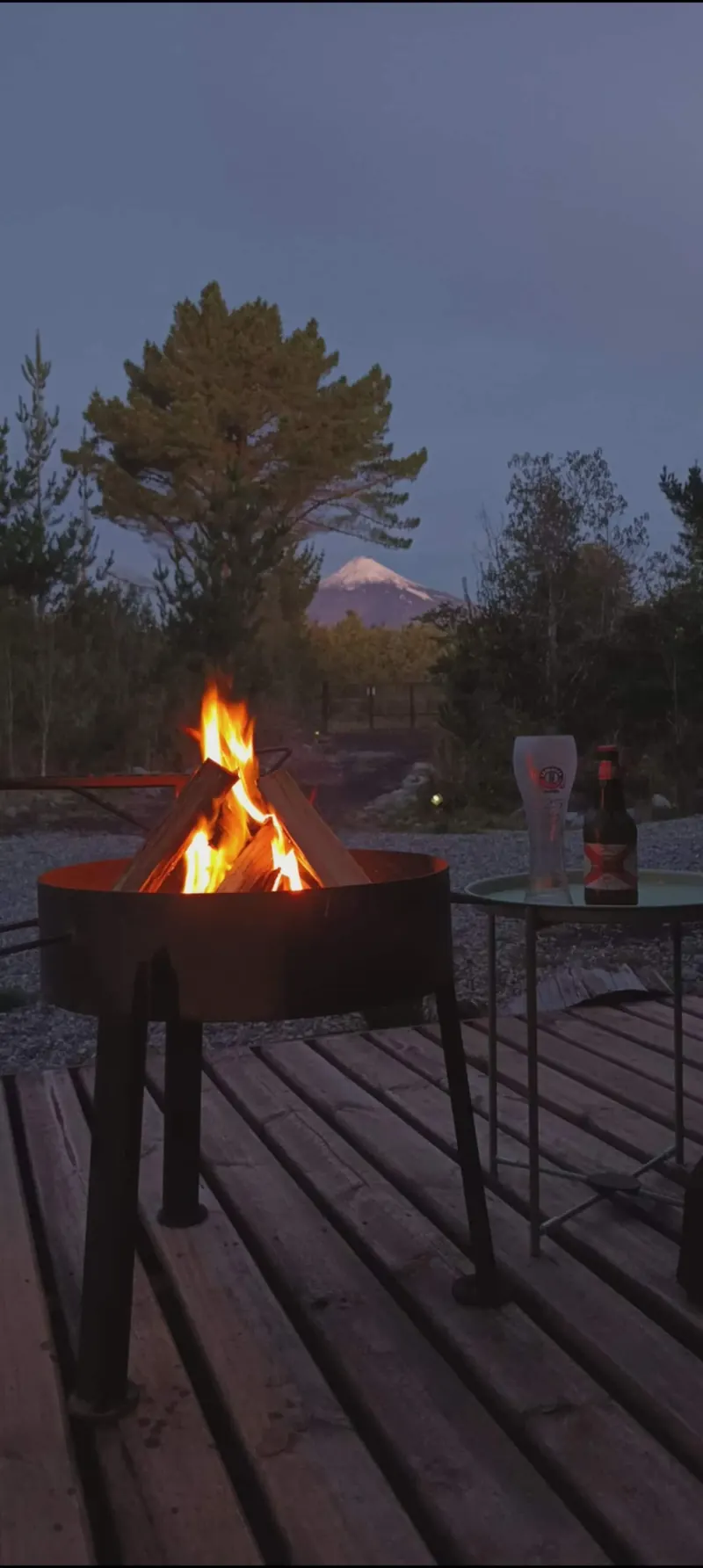 Fire pit burning on the deck at dusk, with the volcano in the background
