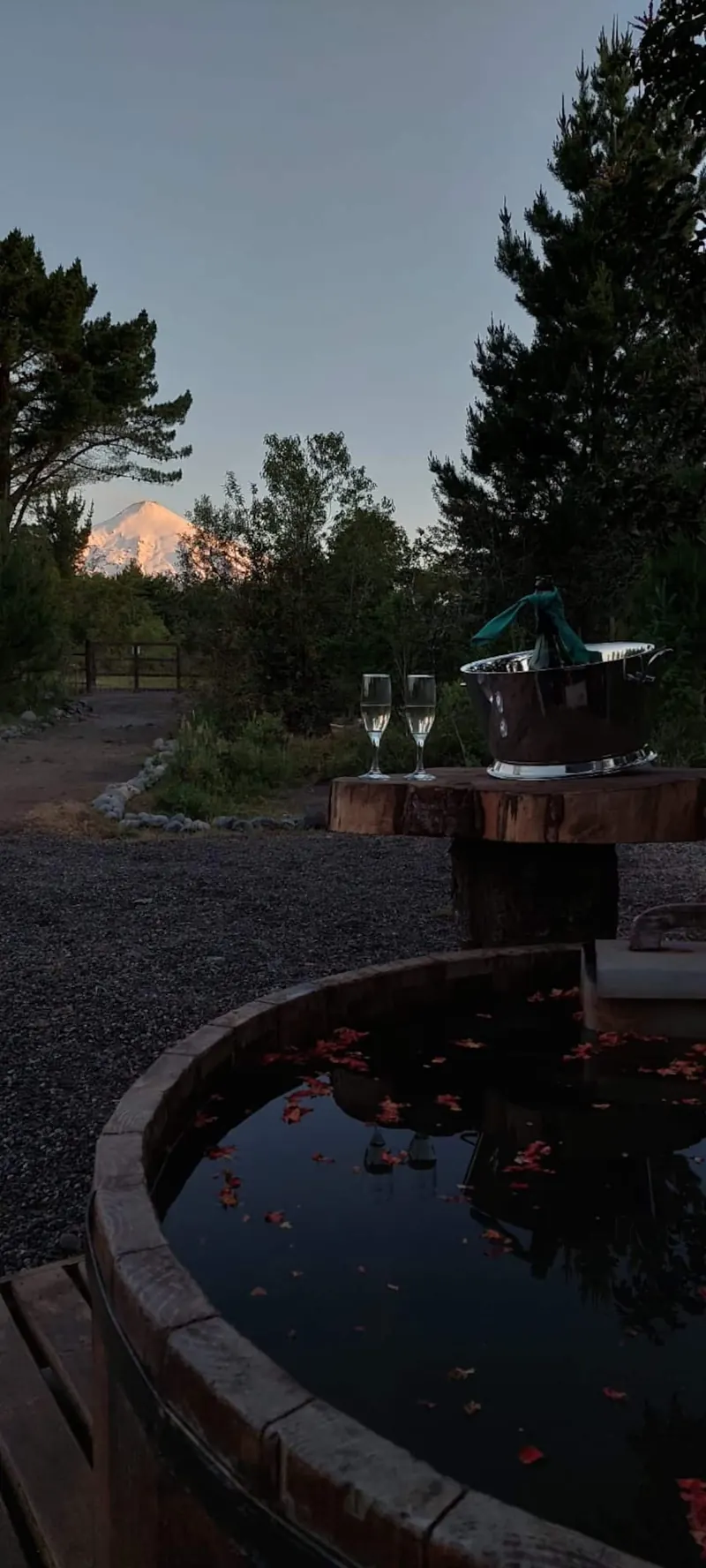 Wooden hot tub with petals and sparkling wine, with the volcano in the background